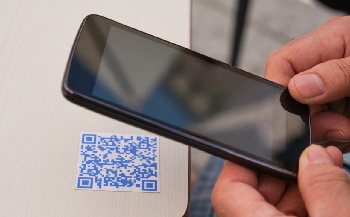 Man hand using the smartphone to scan the QR code in a bar table.